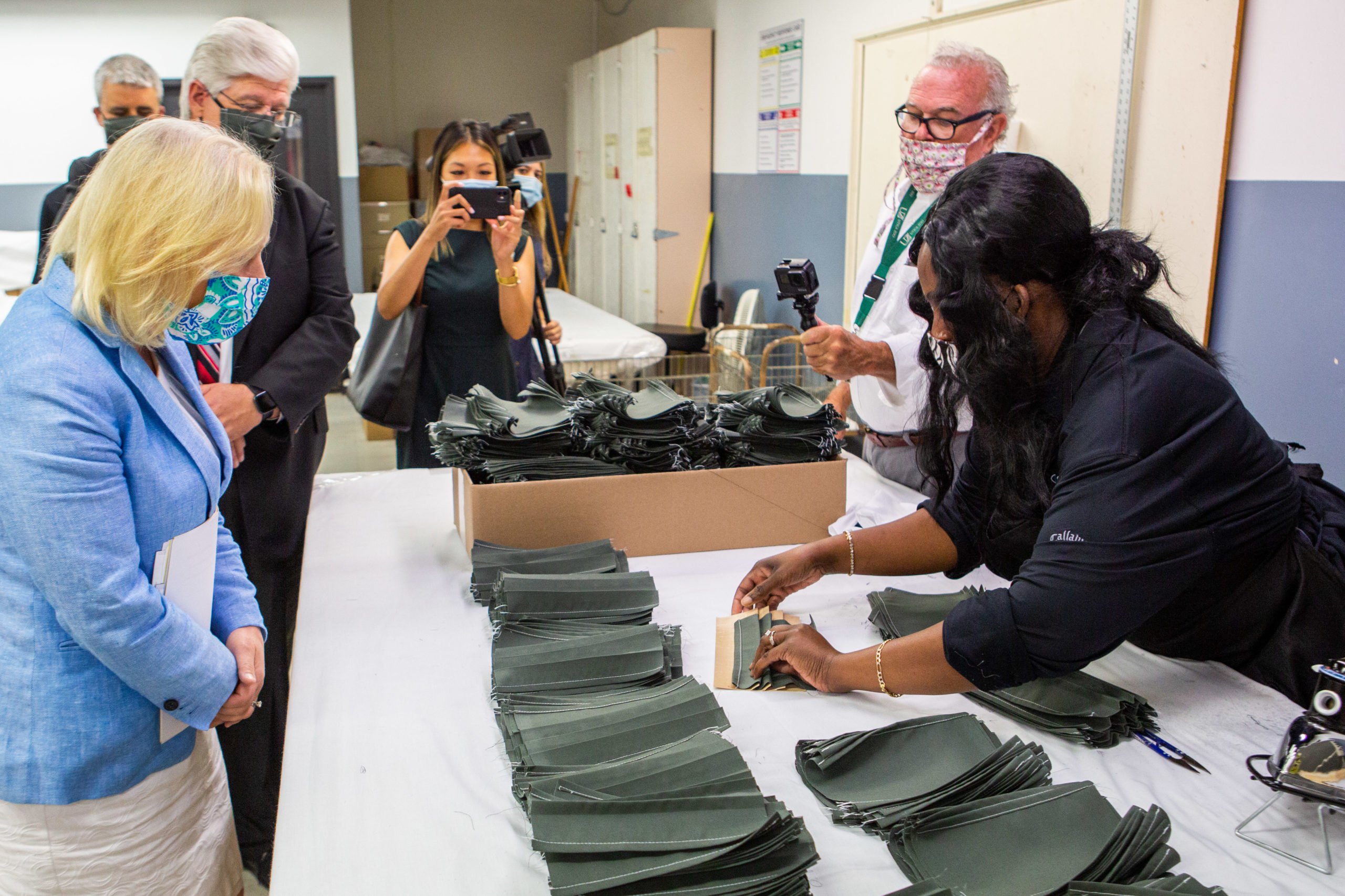 A Central Industries employee showing Senator Gillibrand how masks are produced in the agency.