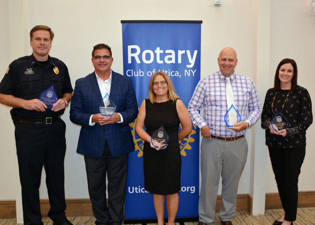 A group of people standing with awards in front of a Rotary banner