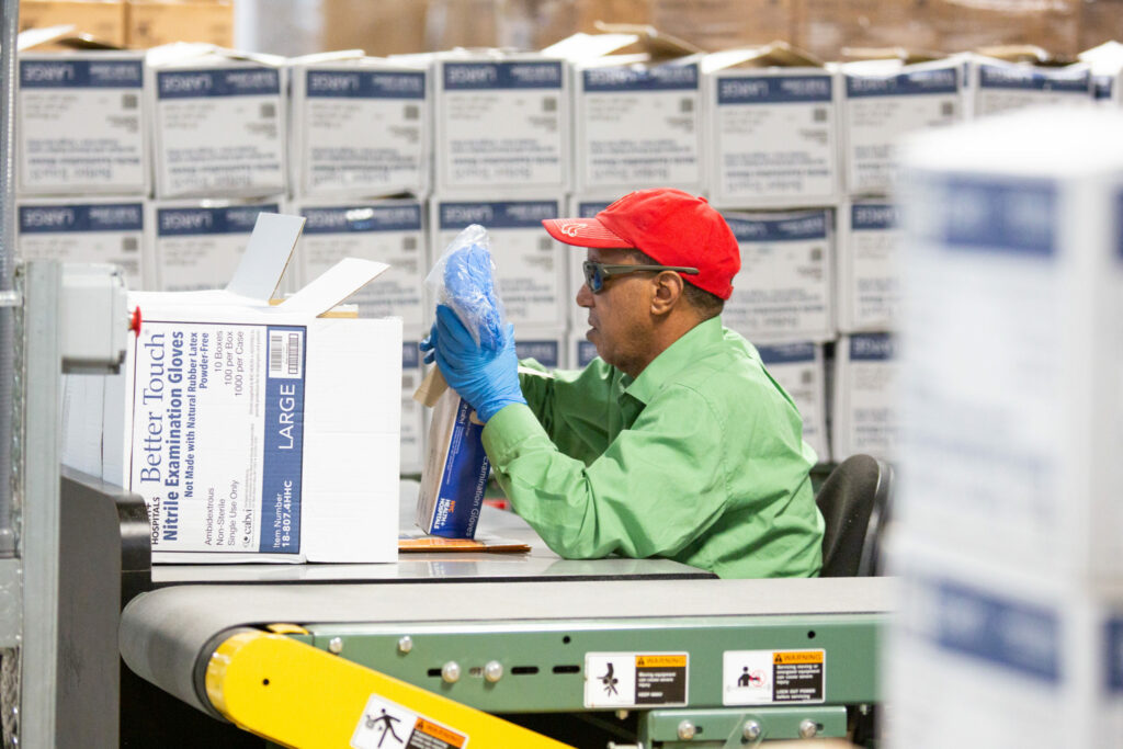 A material handler putting gloves into a box.