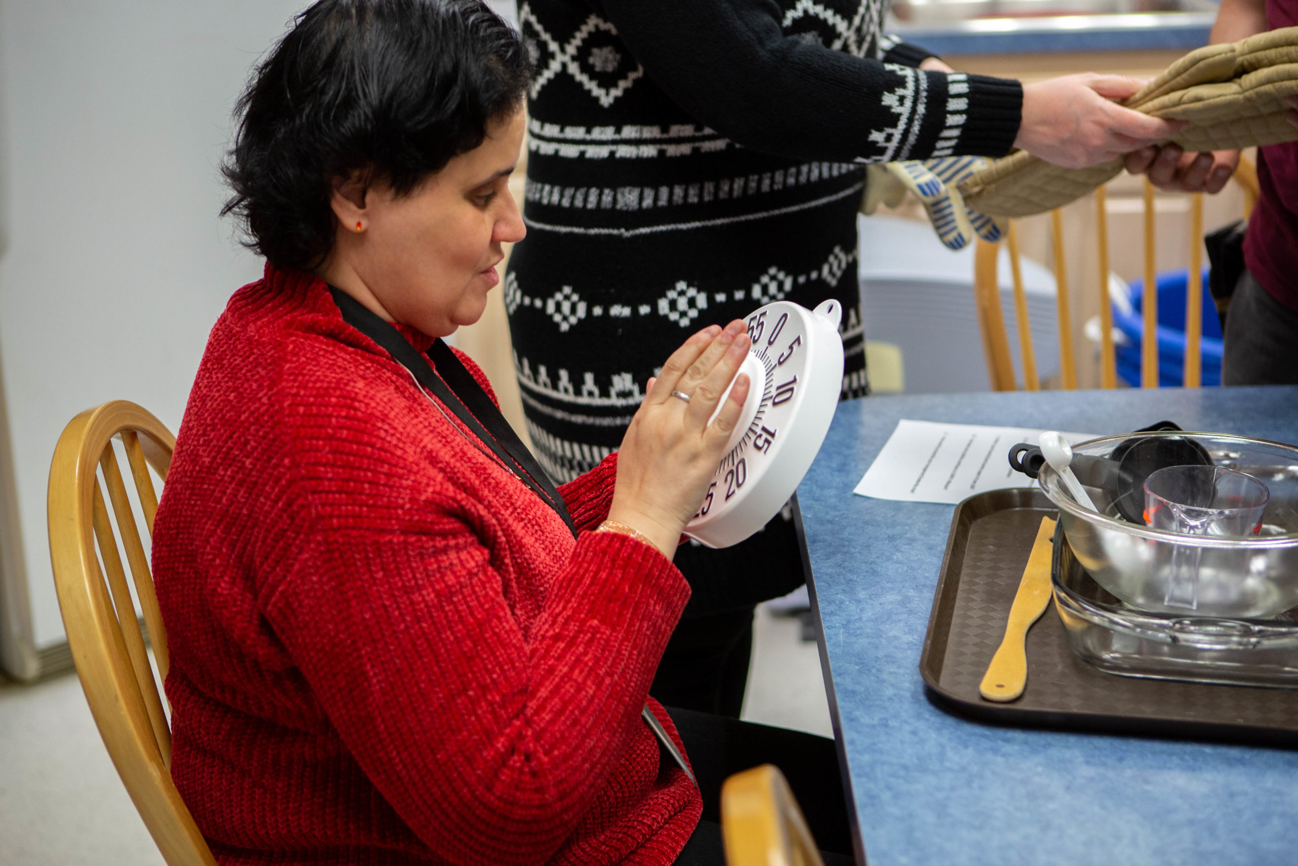 A female with a red sweater is rotating a timer for her meal preparation