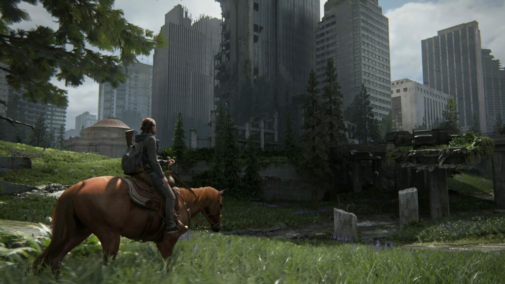 A screenshot of the video game "The Last of Us Part 2". Ellie, the main character, is riding a horse into a abandoned city.