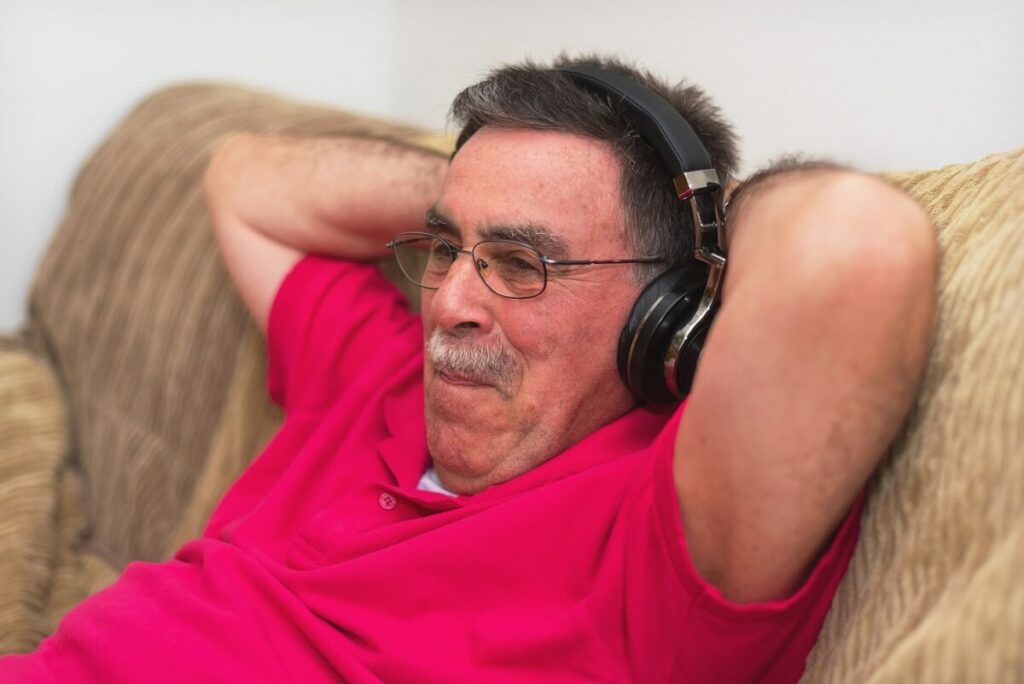 A man on a couch listening through headphones