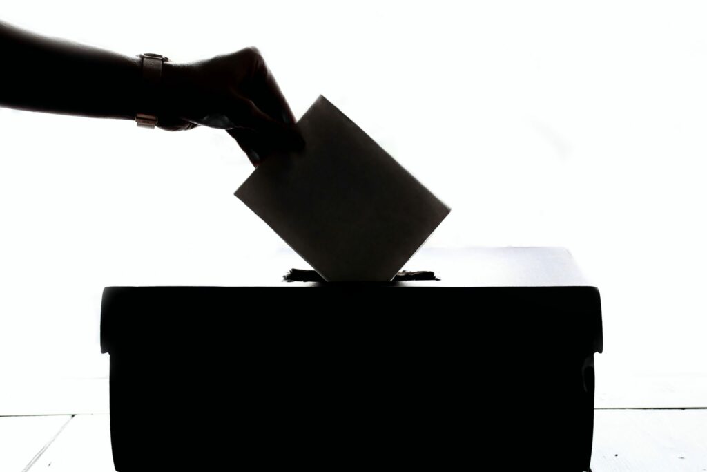 A hand putting a piece of paper in a ballot box